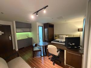 a room with a bed and a desk with a computer at Hotel Alameda Campinas Paulista in São Paulo