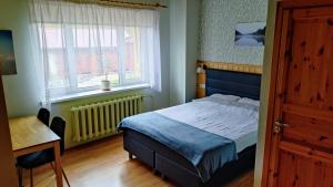 a bedroom with a bed and a desk and a window at Jõesuu Home Accommodation in Purtsi