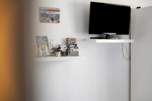 a television on a white wall with shelves at Chambre Saint-Samson-Sur-Rance in Saint-Samson-sur-Rance