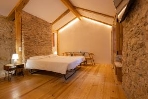 a bedroom with a bed and a brick wall at Casa da Baixa by PURUS in Coimbra