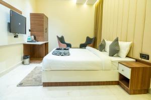 a hotel room with a bed with two chairs and a tv at Hotel Hrishikesh High Tapovan in Rishīkesh