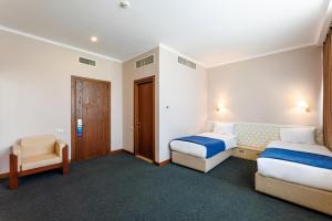 a hotel room with two beds and a chair at Cruise Hotel in Tbilisi City