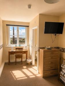 a room with a desk and a television on a wall at The Dolphin Hotel in Wincanton