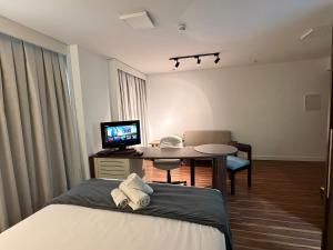 a room with a bed and a desk with a computer at Hotel Alameda Campinas Paulista in São Paulo