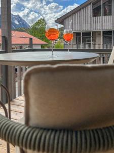 two wine glasses sitting on a table on a balcony at LOEWENHERZ HOMES Mittenwald - Bijou in Mittenwald