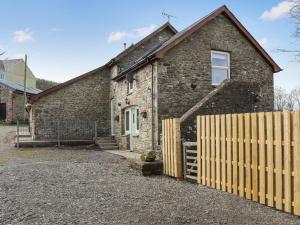a brick house with a wooden fence in front of it at Teifi Cottage - Uk49590 in Llansawel
