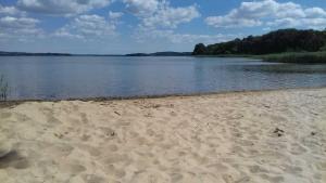 a sandy beach next to a body of water at Ferienwohnung Zum Seeblick in Dahmen +12 photos