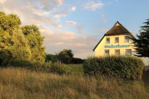 a building with a sign on it in a field at Süderhaus Hiddensee App 7 in Neuendorf