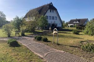 a brick path leading to a white house at Süderhaus Hiddensee App 7 in Neuendorf