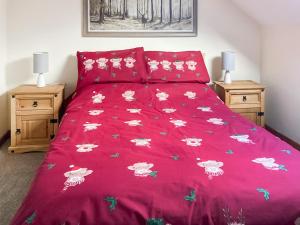 a bed with a red bedspread with flowers on it at Cothi Cottage - Uk49588 in Llansawel