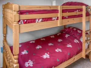 two bunk beds in a room with red sheets at Cothi Cottage - Uk49588 in Llansawel