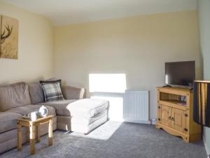 a living room with a couch and a flat screen tv at Benwells Holiday Cottage in Maud +17 photos