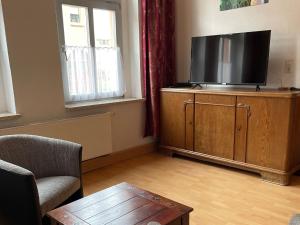 a living room with a flat screen tv on a wooden cabinet at Ferienwohnung Gleißner Hartmann in Sangerhausen