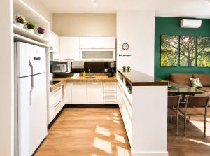 a kitchen with white cabinets and a green wall at Apartamento Vista Jardim in São Domingos
