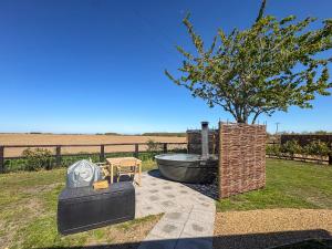 a garden with a tree and a grill and a table at Shepherds Hut - Uk49729 in King's Lynn