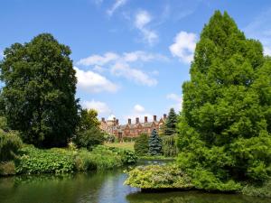 a view of a house from across a river with trees at Shepherds Hut - Uk49729 in King's Lynn +9 photos