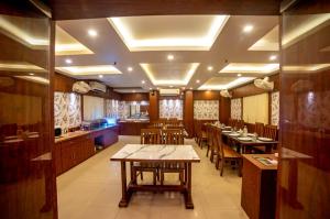 a dining room with tables and chairs and a kitchen at Hotel Sonajhuri in New Digha +28 photos