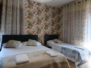 two beds in a bedroom with floral wallpaper at Venice Holiday Apartment in Marghera
