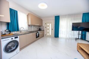 a kitchen with a washer and dryer and blue curtains at Veranda White in Nea Vrasna