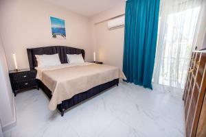 a bedroom with a large bed with blue curtains at Veranda White in Nea Vrasna