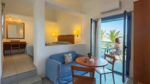 a living room with a couch and a table and a room with a balcony at Palatia Village Hotel Apartments in Hersonissos