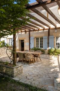 a patio with a table and chairs under a wooden pergola at Maison du Cèdre in Auriac-du-Périgord