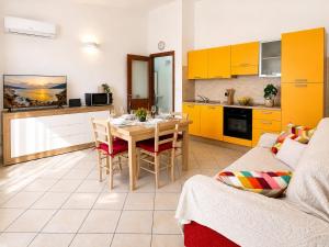 a living room with a table and a kitchen with yellow cabinets at Luna House - Key to Villas in Valledoria