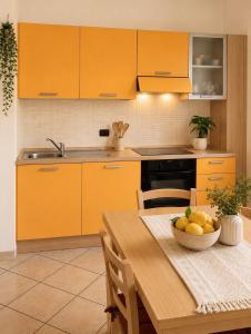 a kitchen with orange cabinets and a table with a bowl of fruit at Luna House - Key to Villas in Valledoria