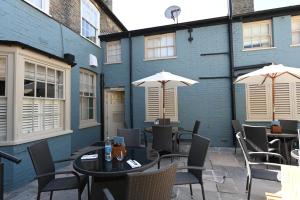 two tables and chairs with umbrellas on a patio at The Bell Hotel, Saxmundham in Saxmundham