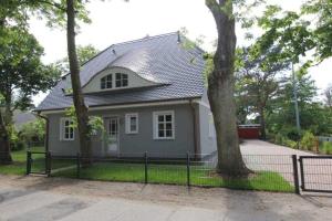a white house with a fence and trees at Haus "Fock" in Prerow