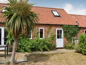a brick house with a palm tree in front of it at The Old Paybarn - Uk39378 in Snettisham