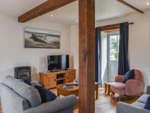 a living room with two couches and a tv at The Old Paybarn - Uk39378 in Snettisham