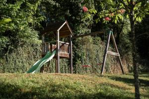 a playground with a green slide in a park at Maison du Cèdre in Auriac-du-Périgord
