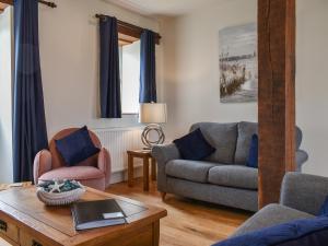 a living room with a couch and a table at The Old Paybarn - Uk39378 in Snettisham +12 photos