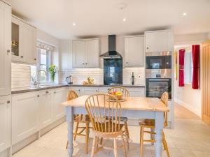 a kitchen with white cabinets and a table and chairs at Paddock Barn in North Nibley