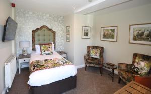 a bedroom with a bed and two chairs at The Golden Fleece Hotel, Thirsk, North Yorkshire - The Coaching Inn Group in Thirsk