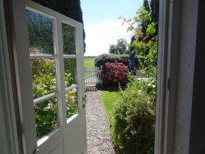 an open door leading to a garden with flowers at Luckow Georg Asmussen Haus in Pommerby