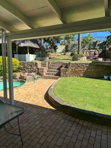 a patio with a stone wall and a swimming pool at Royaltics Lumina house in Weltevredenpark