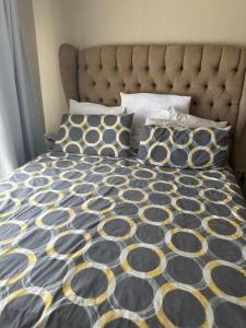 a bed with a black and yellow comforter and pillows at Royaltics Lumina house in Weltevredenpark +5 photos