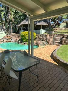 a patio with a table and chairs next to a swimming pool at Royaltics Lumina house in Weltevredenpark