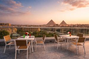 a patio with tables and chairs overlooking the pyramids at Occidental Cairo Grand Museum in Cairo