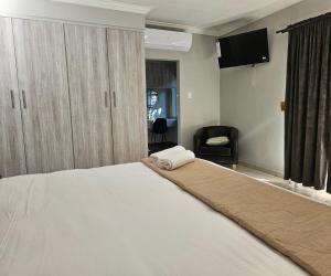 a bedroom with a large white bed and a television at Oblique Boutique House in Centurion +33 photos