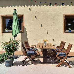a wooden table and chairs with a green umbrella at Ferienhaus Bayerlipp in Scheßlitz