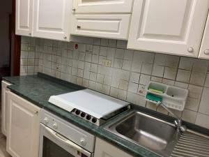 a kitchen with white cabinets and a sink at Delfino in Letojanni