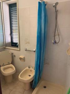 a bathroom with a toilet and a blue shower curtain at Delfino in Letojanni