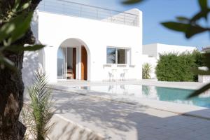 a white house with a swimming pool in front of it at Villa Zain in Houmt Souk