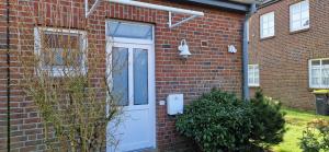 a brick house with a white door and a window at Nr 97 - Ferienhaus Uferstraße in Carolinensiel
