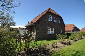 a brown brick house with an umbrella in the yard at Nr 96 - Ferienhaus Uferstraße in Carolinensiel
