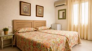 a bedroom with a bed with a floral bedspread at Hostal Muriel in Aljaraque