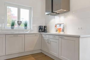 a white kitchen with white cabinets and a window at Fennenblick in List